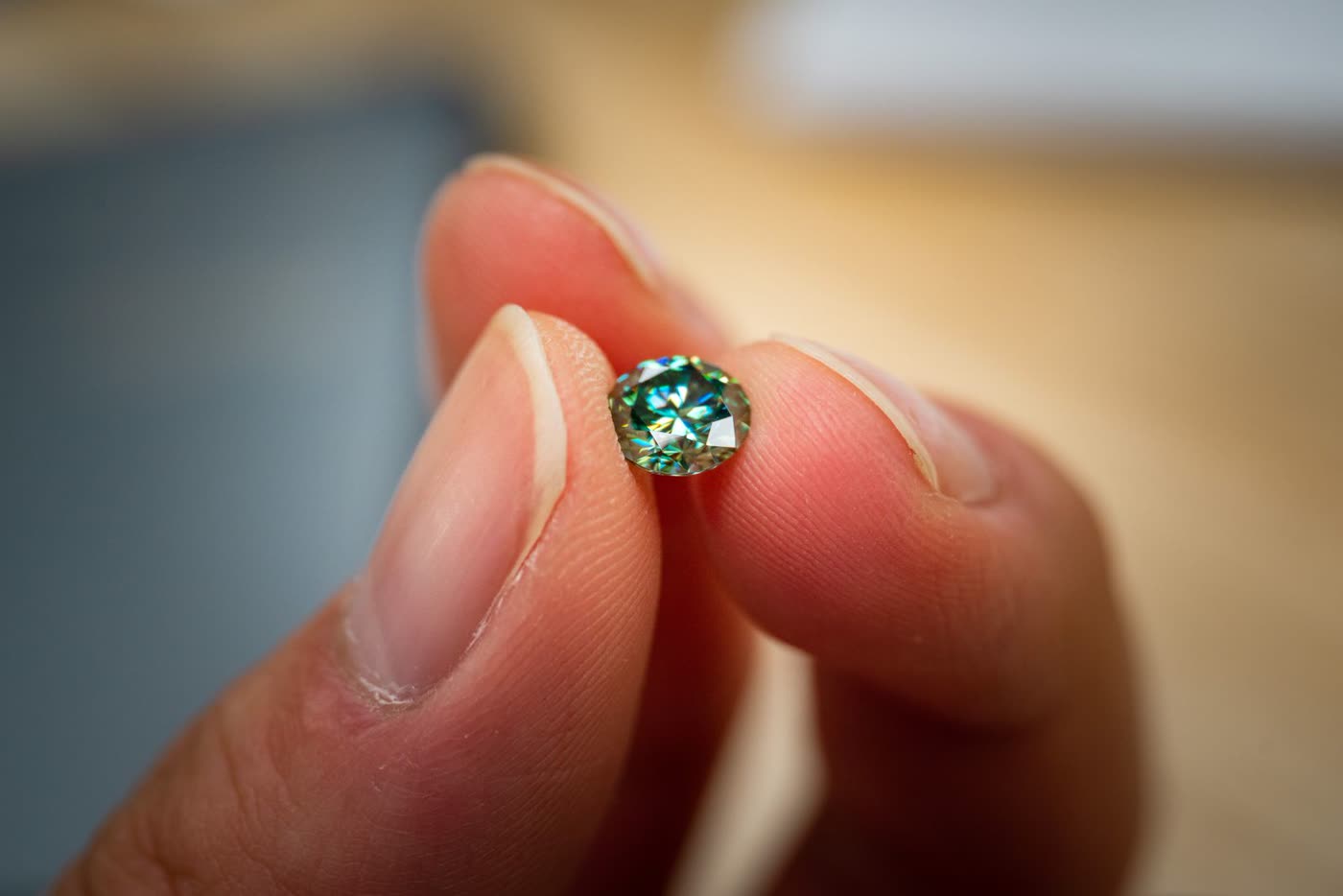 A macro close-up of a cut gemstone held between two fingertips, catching the light