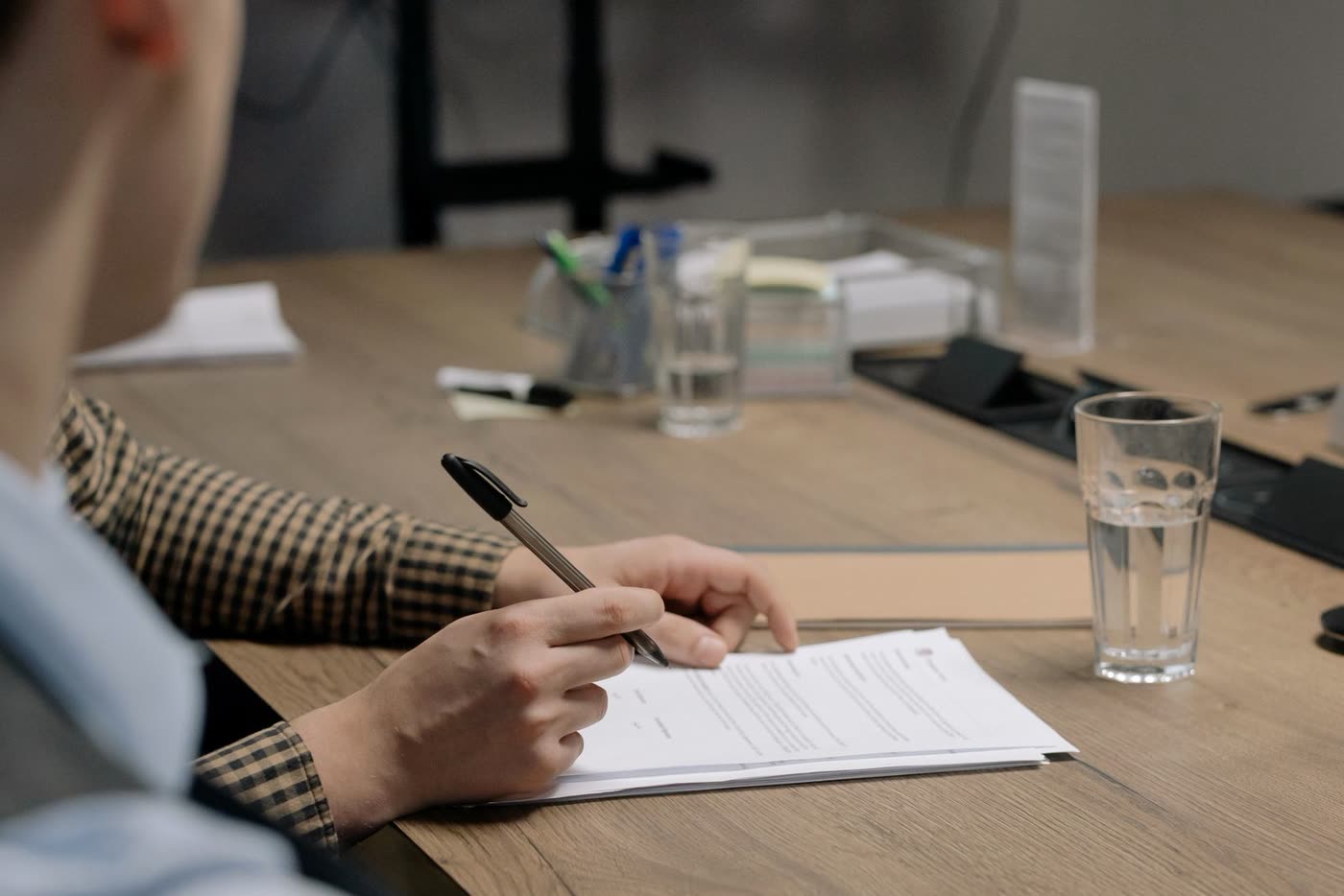 A person reviewing a printed document with a pen in hand