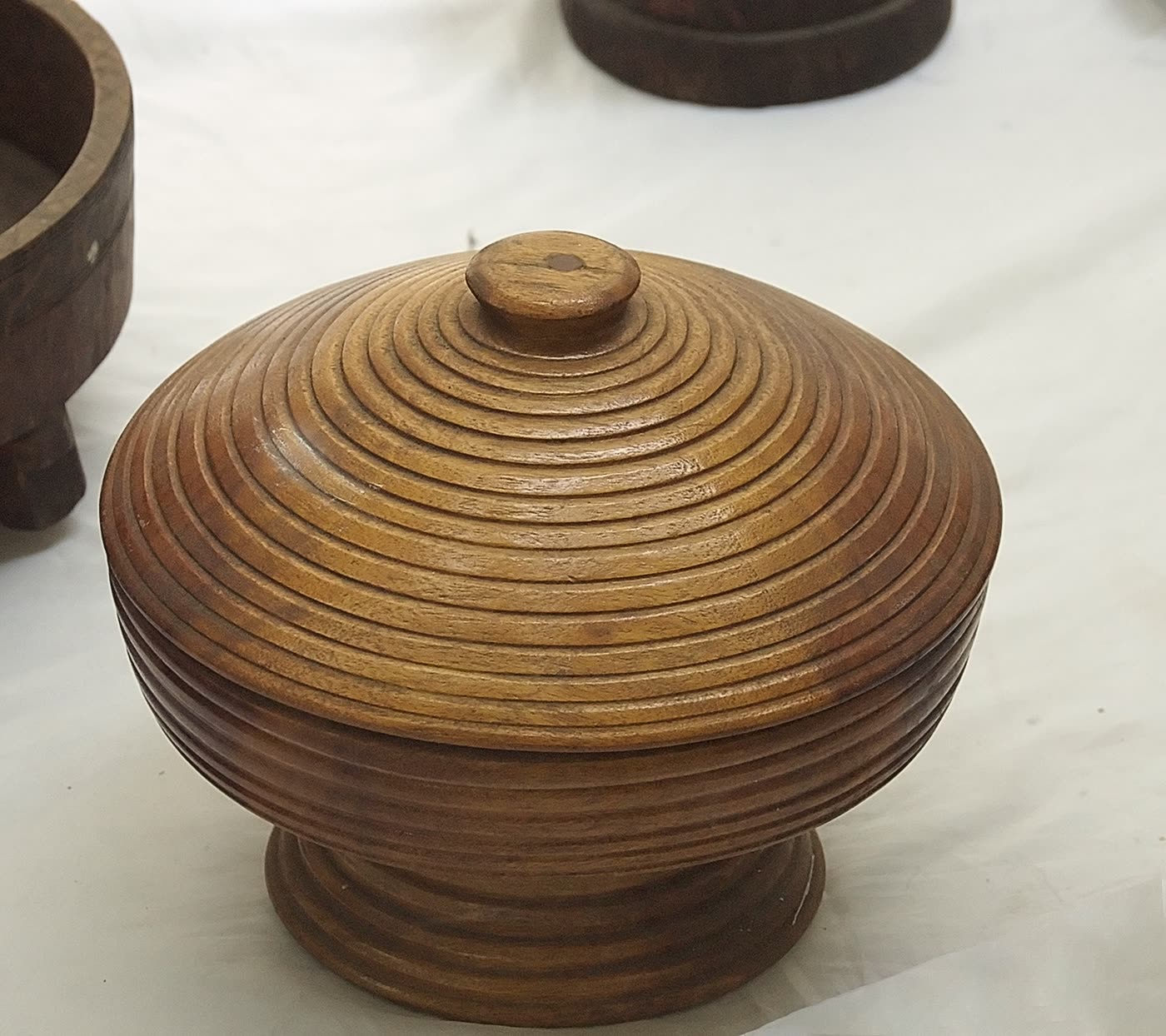 A round, turned wooden lidded vessel with a ridged concentric pattern